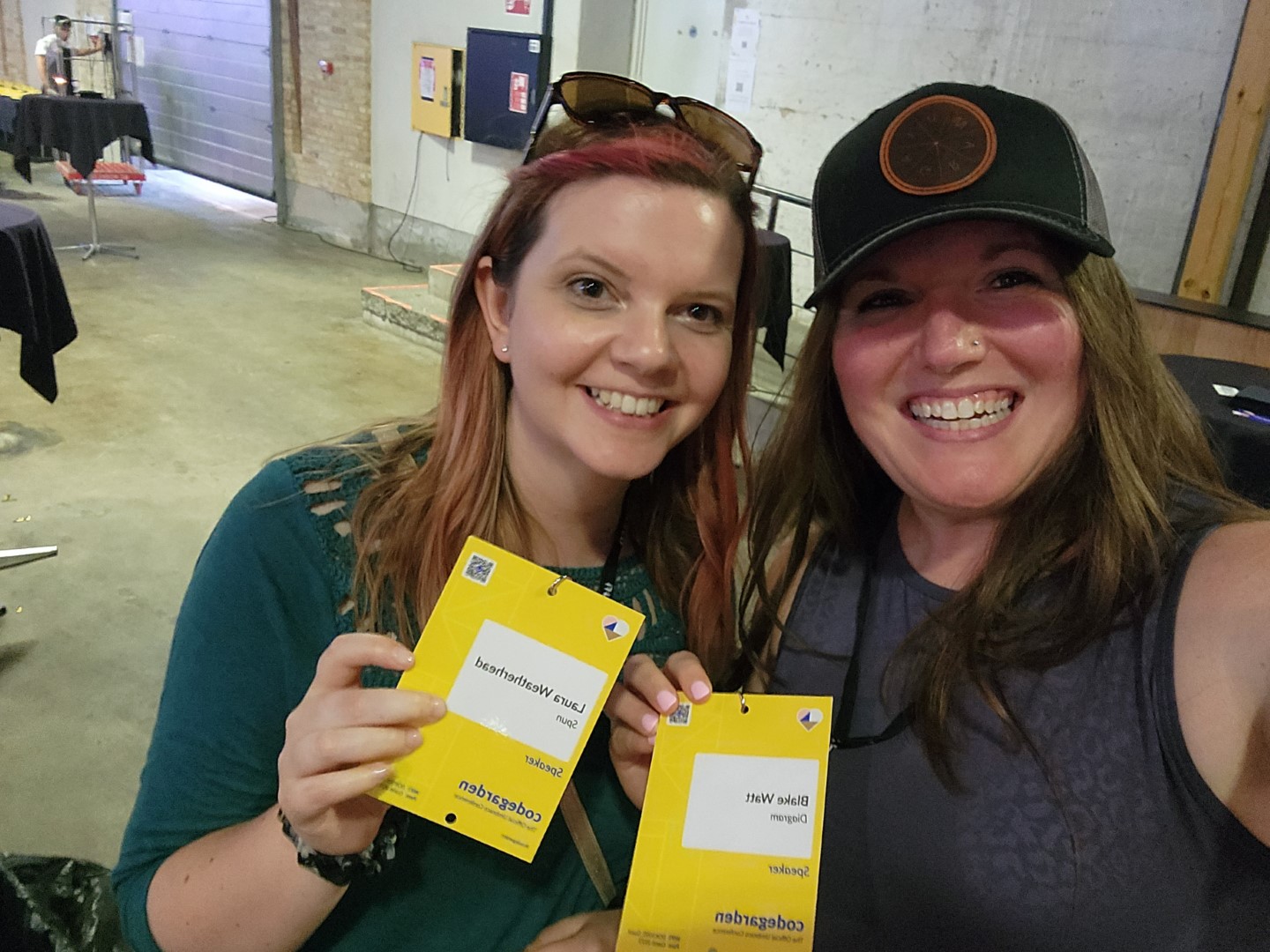 Blake and Laura smiling and holding their speaker badges.